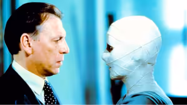 Dr. Philip Channard (Kenneth Cranham) faces bandage-wrapped Julia Cotton in a hospital corridor