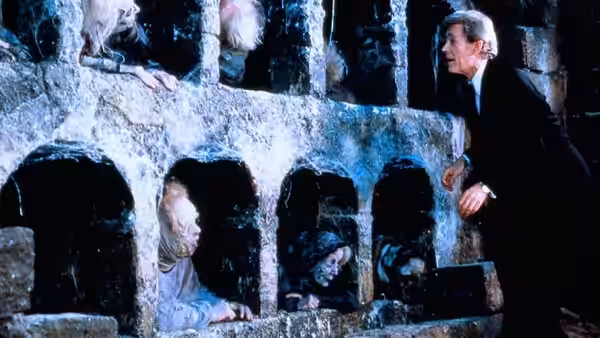 Peter Plunkett (Peter O'Toole) peers at ghostly figures behind openings in a stone wall