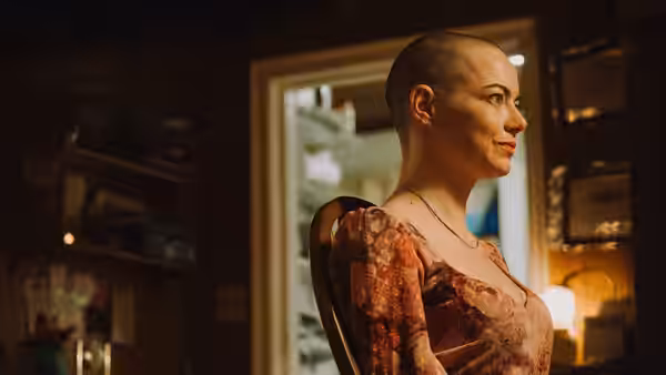 Michelle (Emma Stone) in a floral dress sits indoors looking to her right
