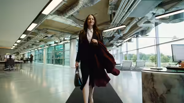 Michelle (Emma Stone) walks through a bright office lobby carrying her coat