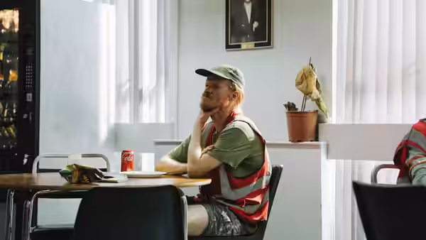 Teddy (Jesse Plemons) sits at a diner table wearing a high-vis vest and cap