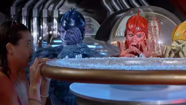 Valerie and the colorful aliens peer over an icy basin in a futuristic room