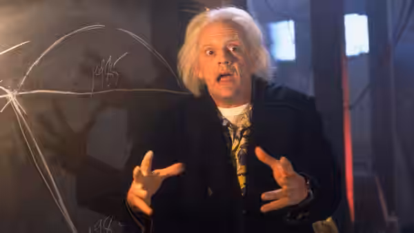 Doc Brown (Christopher Lloyd) gestures beside a chalkboard in his laboratory