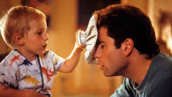 Mikey reaches up to press a cloth against James (John Travolta)'s face