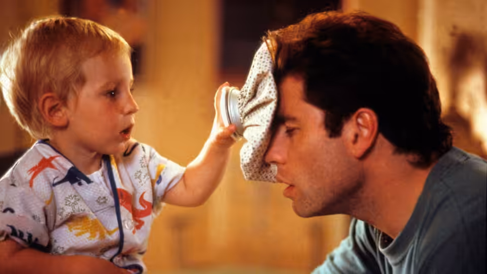 Mikey reaches up to press a cloth against James (John Travolta)'s face