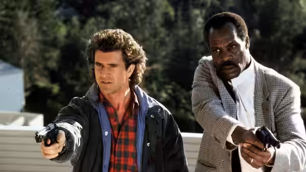 Martin Riggs (Mel Gibson) and Roger Murtaugh (Danny Glover) aim pistols outdoors