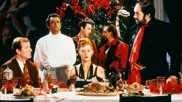 Georgina Spica (Helen Mirren) sits at dinner as Albert Spica (Michael Gambon) stands beside her