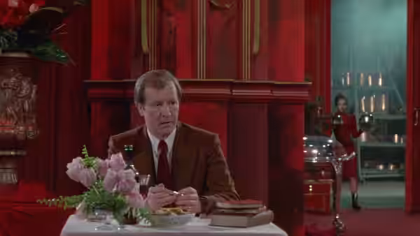 A suited diner sits alone at a table in the red-paneled restaurant