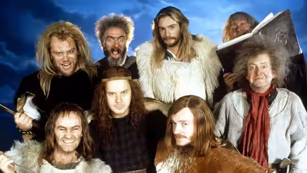 A group of Vikings in fur and medieval clothing gather, one carrying a large axe