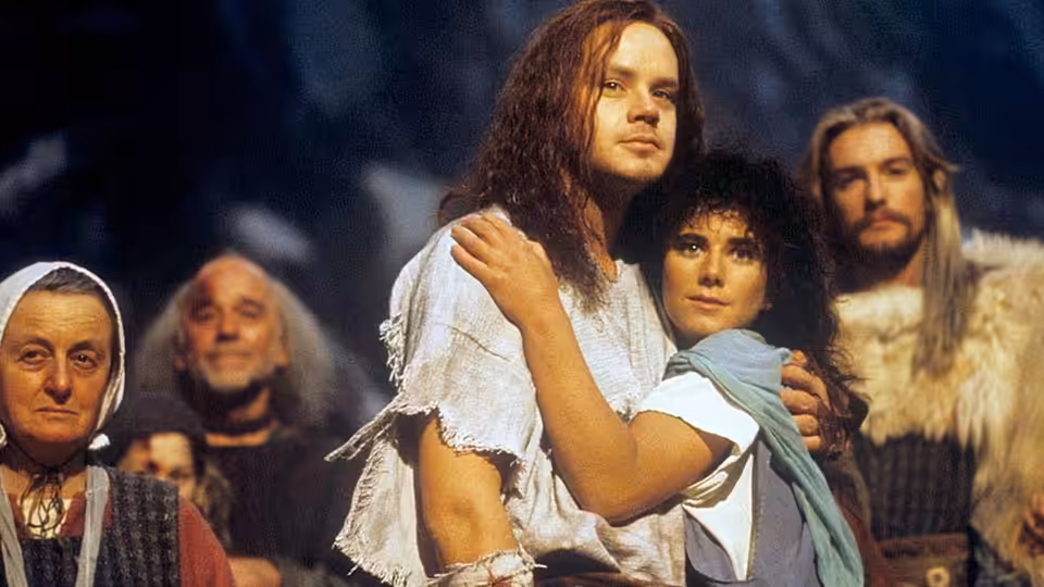 Erik (Tim Robbins) stands embraced by a woman as villagers gather around them