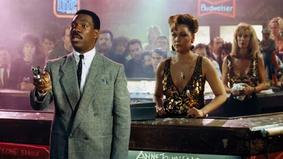 Reggie Hammond (Eddie Murphy) holds a gun beside a woman at a crowded bar