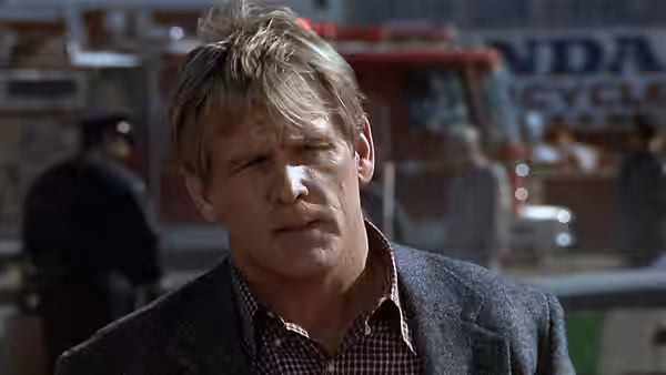 Jack Cates (Nick Nolte) stands on a city street beside parked emergency vehicles