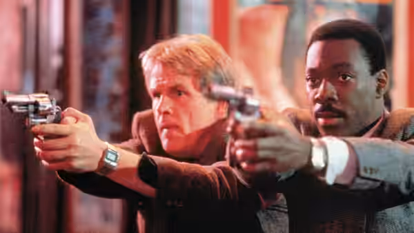 Jack Cates (Nick Nolte) and Reggie Hammond (Eddie Murphy) aim pistols down a city street