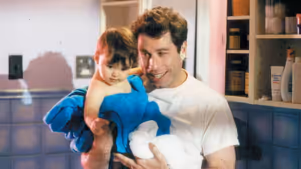 James (John Travolta) holds a baby wrapped in a blue towel