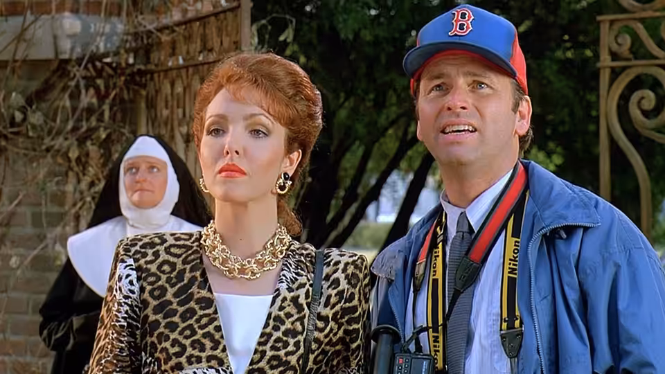 Ben (John Ritter) and Flo (Amy Yasbeck) look upward outdoors, with a nun behind them