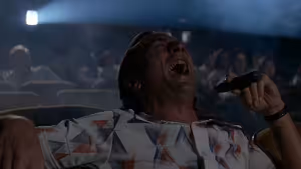 Max Cady (Robert De Niro) throws back his head laughing, holding a small dark object