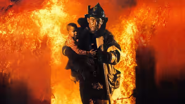 A firefighter carries a child through a wall of flames