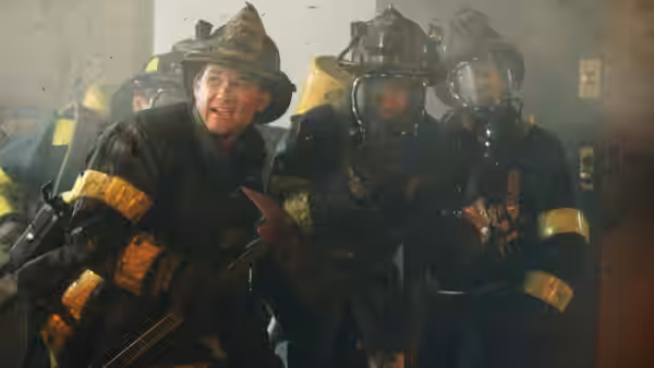 Firefighters in protective gear advance through a smoke-filled building