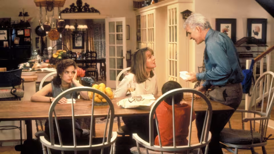 George Banks (Steve Martin) talks with Nina and Annie at the family kitchen table