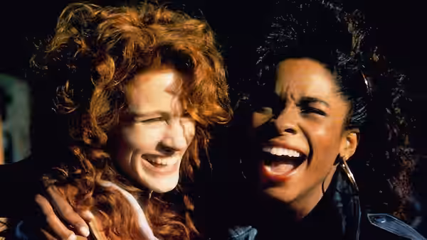Hilary O'Neil (Julia Roberts) laughs beside a woman in a dark setting