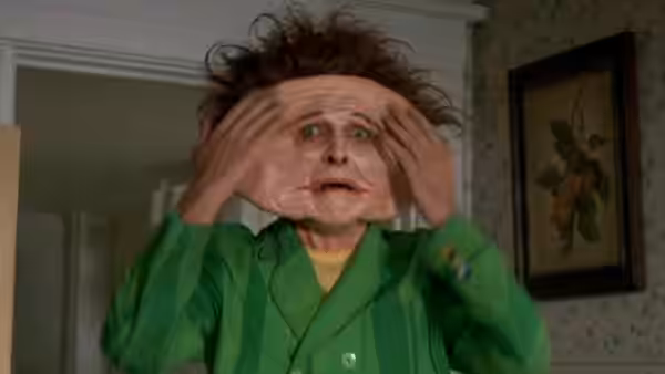 Drop Dead Fred (Rik Mayall) pulls at his face inside a house
