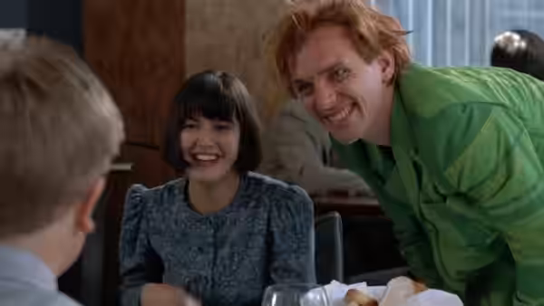 Elizabeth (Phoebe Cates) smiles beside Drop Dead Fred (Rik Mayall) at a dining table