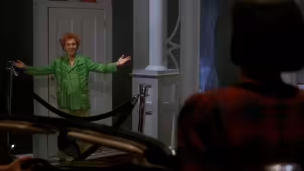 Drop Dead Fred (Rik Mayall) spreads his arms in a doorway as a woman watches