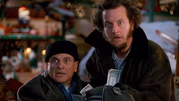 Harry (Joe Pesci) and Marv (Daniel Stern) peer over a bag of cash amid Christmas decorations