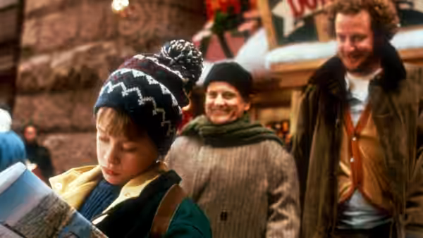 Kevin (Macaulay Culkin) reads a map while Harry and Marv approach on a city street