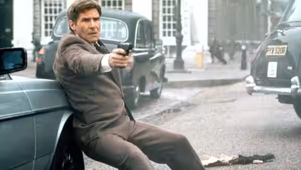 Jack Ryan (Harrison Ford) fires a handgun from beside a car on a city street