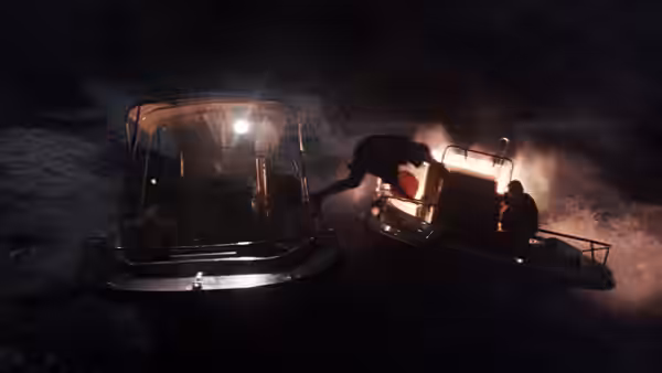 People transfer between boats as one vessel burns in the darkness