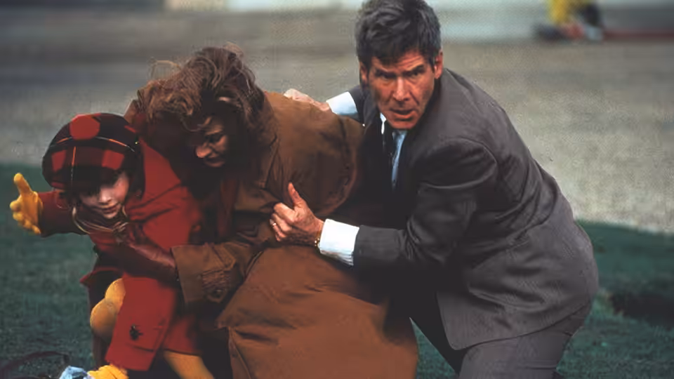 Jack Ryan (Harrison Ford) shields Cathy and Sally from danger outdoors