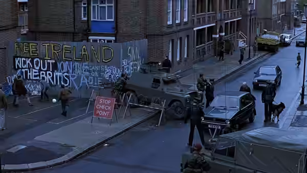 Soldiers and police guard an armored vehicle at a Belfast street checkpoint beside protest graffiti