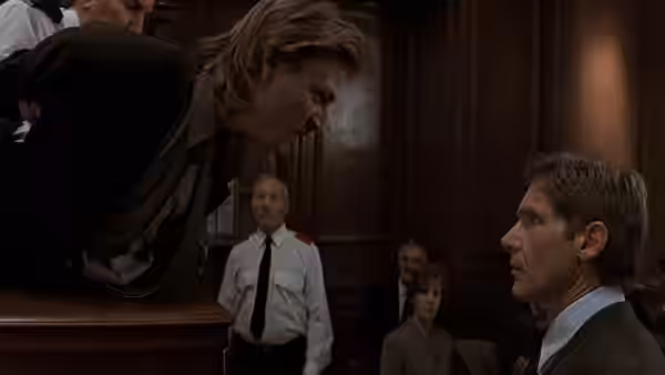 Jack Ryan listens as a man leans across the courtroom rail