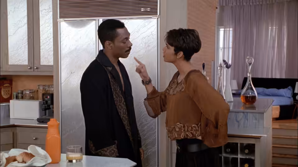 Marcus Graham faces Jacqueline in a kitchen as she gestures toward him