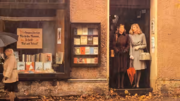 Two women stand in a doorway beside a bookshop window