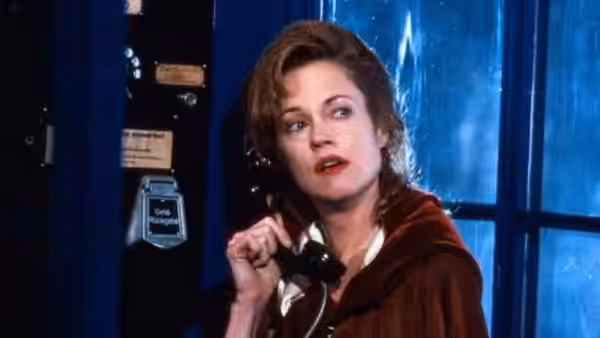 Linda Voss (Melanie Griffith) speaks on a telephone beside a blue-lit window