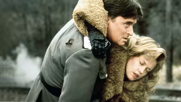 Ed Leland (Michael Douglas) carries the unconscious Linda Voss (Melanie Griffith) outdoors