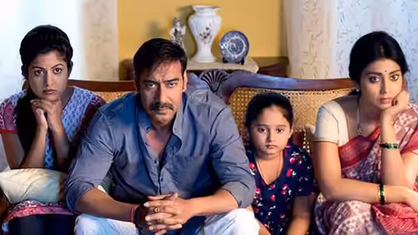 Vijay Salgaonkar (Ajay Devgn) seated with his wife and daughters on a sofa