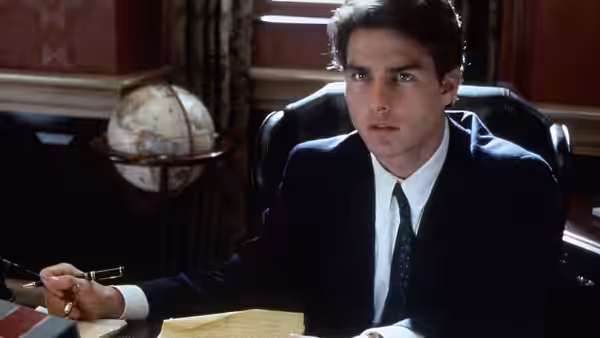 Mitch McDeere (Tom Cruise) sits at a desk holding a pen