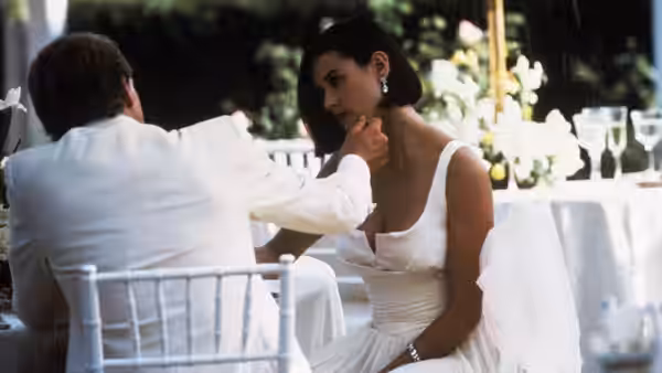 John Gage (Robert Redford) reaches toward Diana Murphy (Demi Moore) at an outdoor table