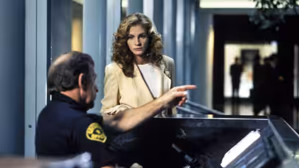 Darby Shaw (Julia Roberts) speaks with a uniformed security guard at a building entrance