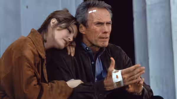 Lilly Raines (Rene Russo) rests her head on Frank Horrigan (Clint Eastwood) as he examines his bandaged hand