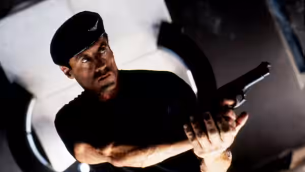 John Spartan (Sylvester Stallone) aims a pistol while wearing a black beret