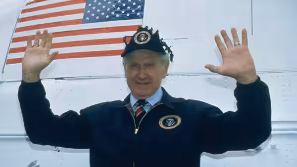 President Thomas Benson (Lloyd Bridges) raises both hands before an aircraft bearing an American flag