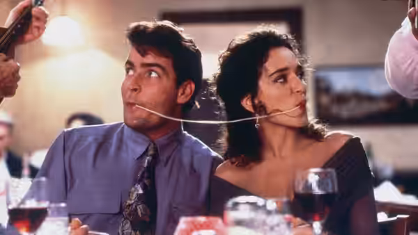 Topper Harley (Charlie Sheen) and Ramada (Valeria Golino) sit together at a dinner table