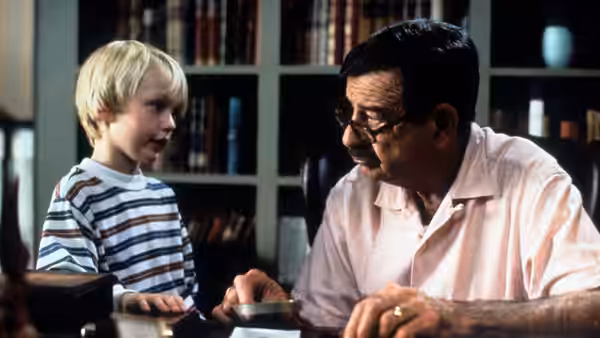 Dennis Mitchell (Mason Gamble) talks with Mr. Wilson (Walter Matthau) at a desk