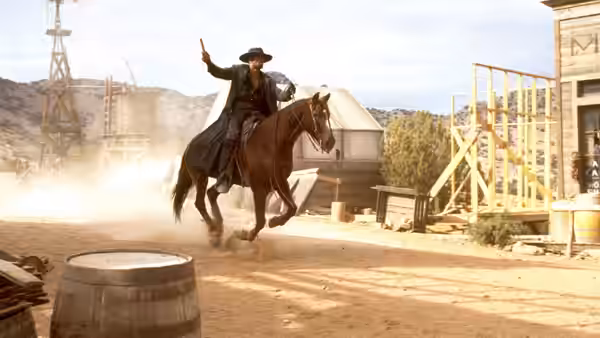 Jesse Lee (Mario Van Peebles) rides a horse through a dusty town, raising one hand