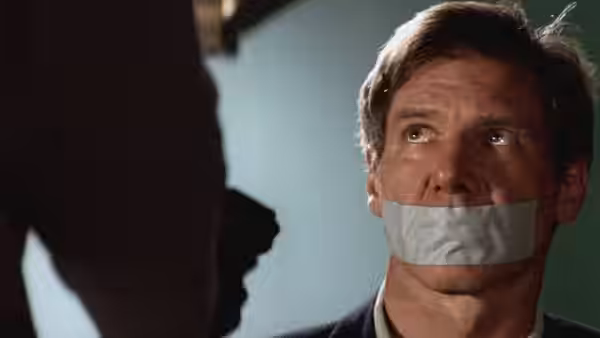 Jack Ryan (Harrison Ford) sits with his mouth taped, facing a shadowy figure