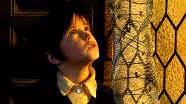 Ana (Ana Torrent) gazes upward beside a window with netting